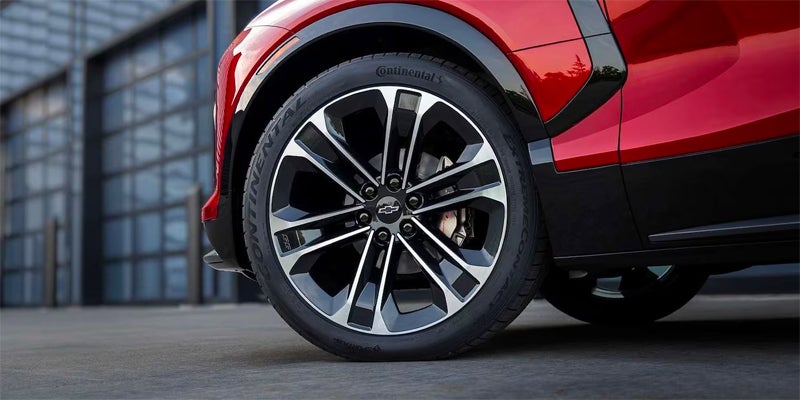Driver side wheel and tire of an all-new Radiant Red 2024 Chevrolet vehicle. Rims are black and silver. - Ted Britt Chevrolet Sterling, VA
