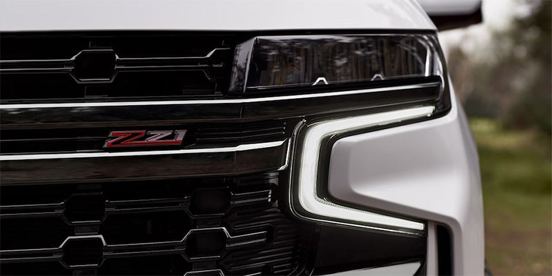 Close-up shot of a white 2024 Chevrolet Tahoe's front driver side headlight and grill. - Ted Britt Chevrolet Sterling, VA
