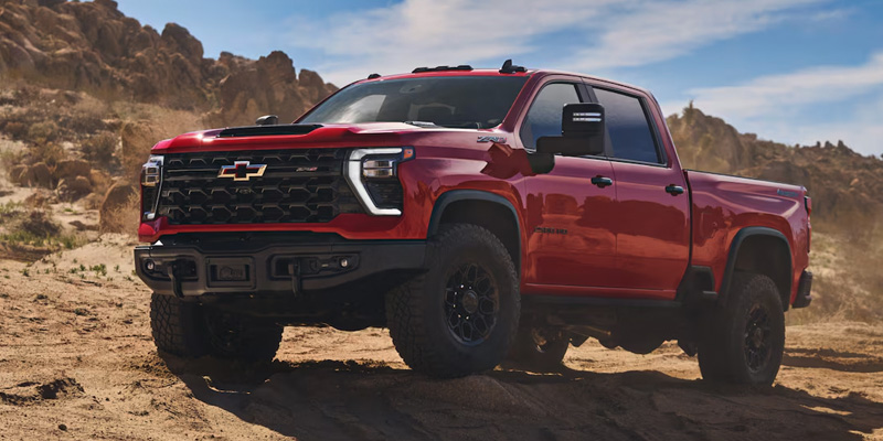 an all-new red 2025 Chevrolet Silverado 2500HD parked in a desert.